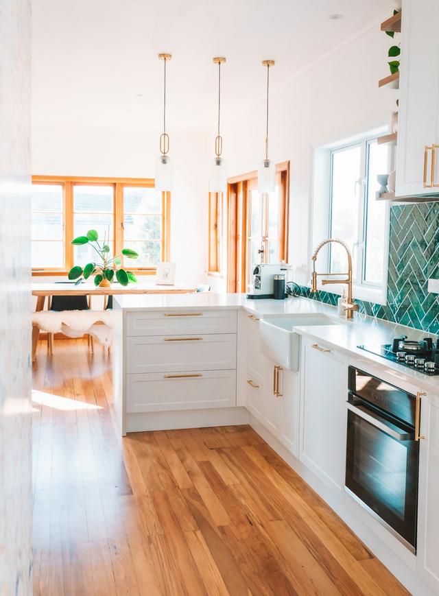 Bright kitchen with white cabinets, brass pendant lights and warm wood floors